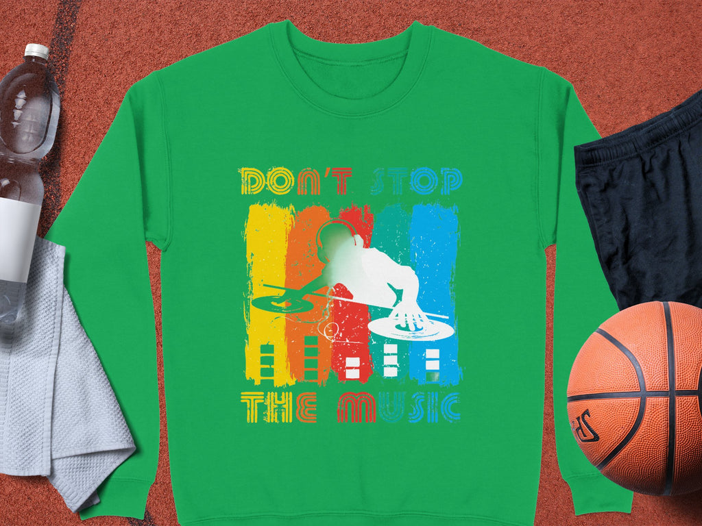 Garment Graphics DJ sweatshirt features a green silhouette of a DJ at turntables, colorful stripes, and the text Dont Stop the Music. Ideal for music lovers, this unisex piece is styled with a basketball and sportswear.