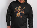 A man in a black hoodie from Garment Graphics, designed for music lovers, showcases a cool gorilla with sunglasses. The ape confidently holds an electric guitar and flashes a peace sign.