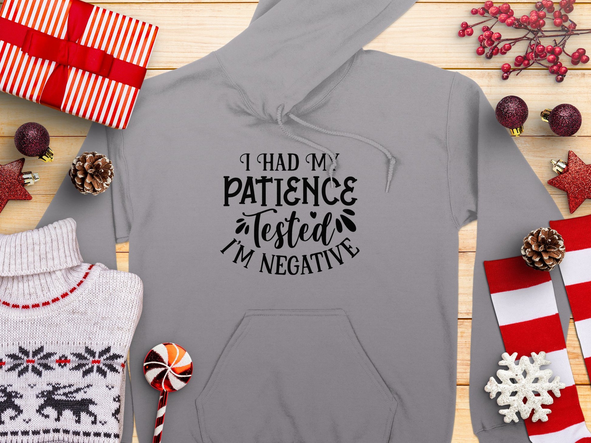 Garment Graphics offers a humorous gray hoodie with I had my patience tested. Im negative surrounded by holiday elements like gifts, pinecones, candy, and festive sweaters—a unique addition to any festive wardrobe.