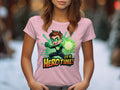 A person in a Garment Graphics pink t-shirt, featuring a vibrant green superhero and the bold words Its Hero Time! against a snowy outdoor backdrop with trees—ideal for young heroes in colorful attire.