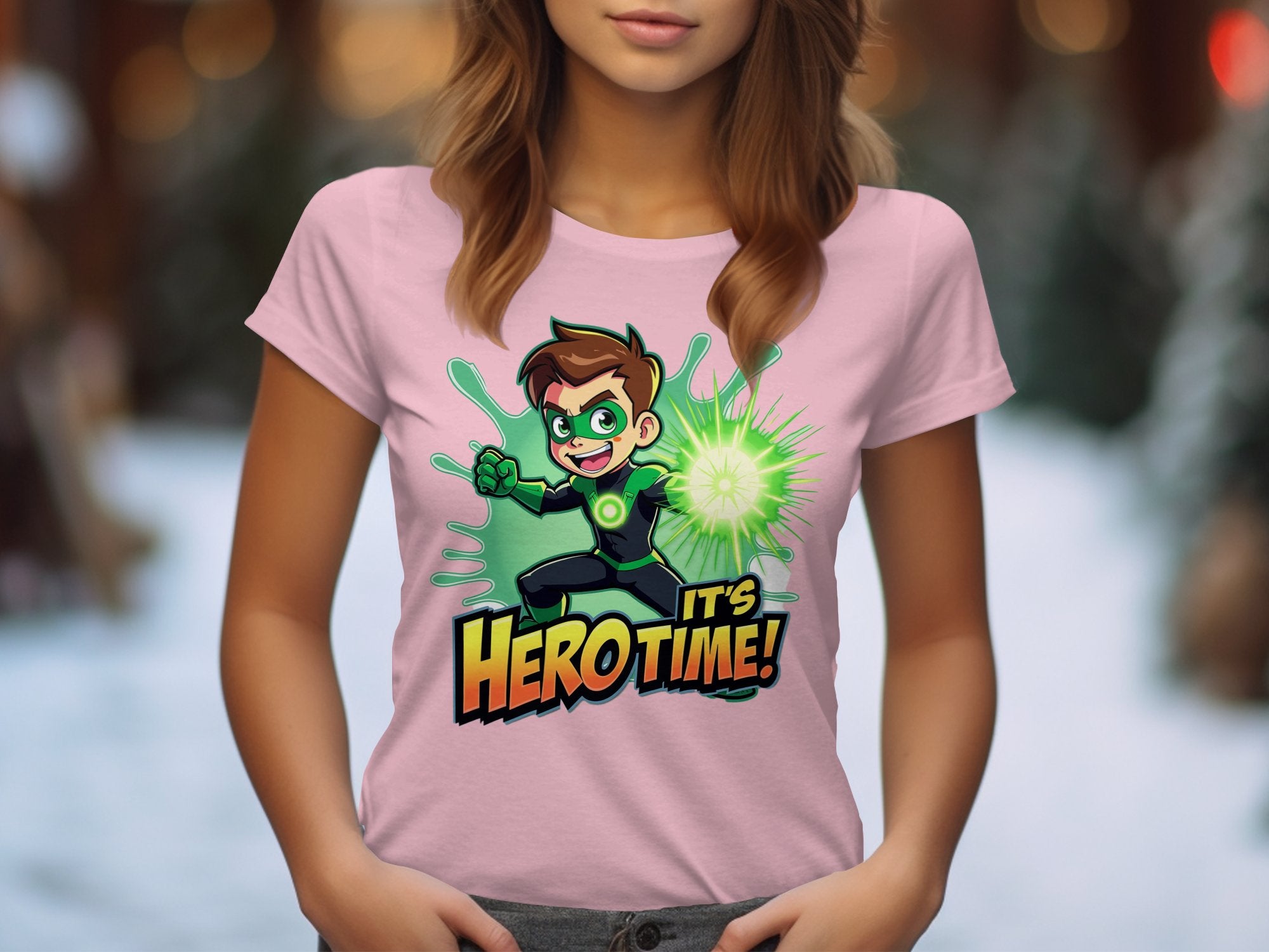 A person in a Garment Graphics pink t-shirt, featuring a vibrant green superhero and the bold words Its Hero Time! against a snowy outdoor backdrop with trees—ideal for young heroes in colorful attire.