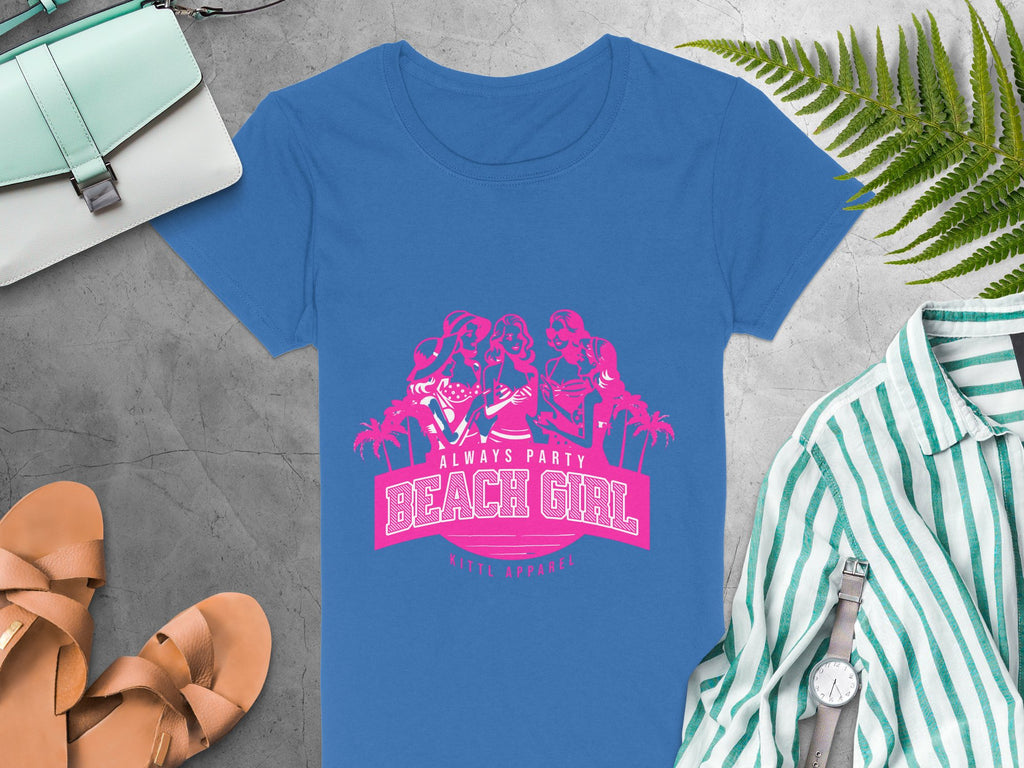 Blue t-shirt featuring a pink graphic of three dancing women with Always Party Beach Girl and Ninth Apparel, surrounded by a purse, sandals, striped shirt, watch, and fern leaves on gray. Ideal for Womens Semi-Fitted Tee lovers from Garment Graphics.