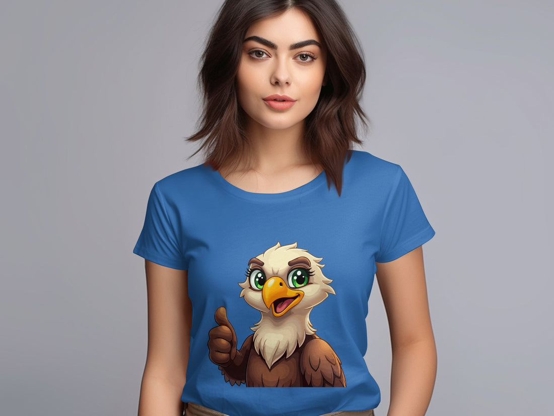 A woman with brown hair wears a Garment Graphics blue cartoon T-shirt featuring an eagle giving a thumbs up, ideal for animal lovers. The background is plain grey.