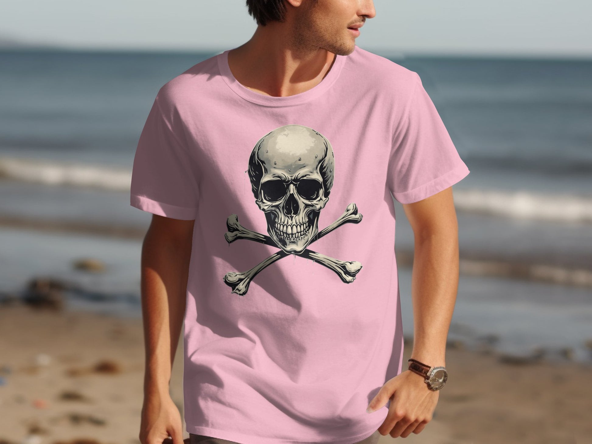 Walking on the sunlit beach, they wear a Garment Graphics light pink T-shirt showcasing a bold skull and crossbones. Their unique fashion pops against the clear sky and shimmering ocean.