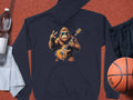 The navy hoodie from Garment Graphics displays a gorilla graphic in sunglasses, playing an electric guitar with a peace sign. Its showcased on a surface alongside a water bottle, towel, basketball, and black shorts.