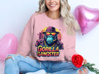 A woman with long, wavy hair exudes urban style in a pink Garment Graphics sweatshirt featuring a Gorilla Gangster image. She sits elegantly, holding a red rose, as two pink heart-shaped balloons float behind her.
