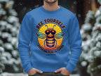 A person wears Garment Graphics blue Summer Edition Sweatshirt featuring a cool bee in sunglasses. The phrase Bee Yourself, Everyone Else is Taken pops against the snowy backdrop, highlighting its unisex sizing allure.