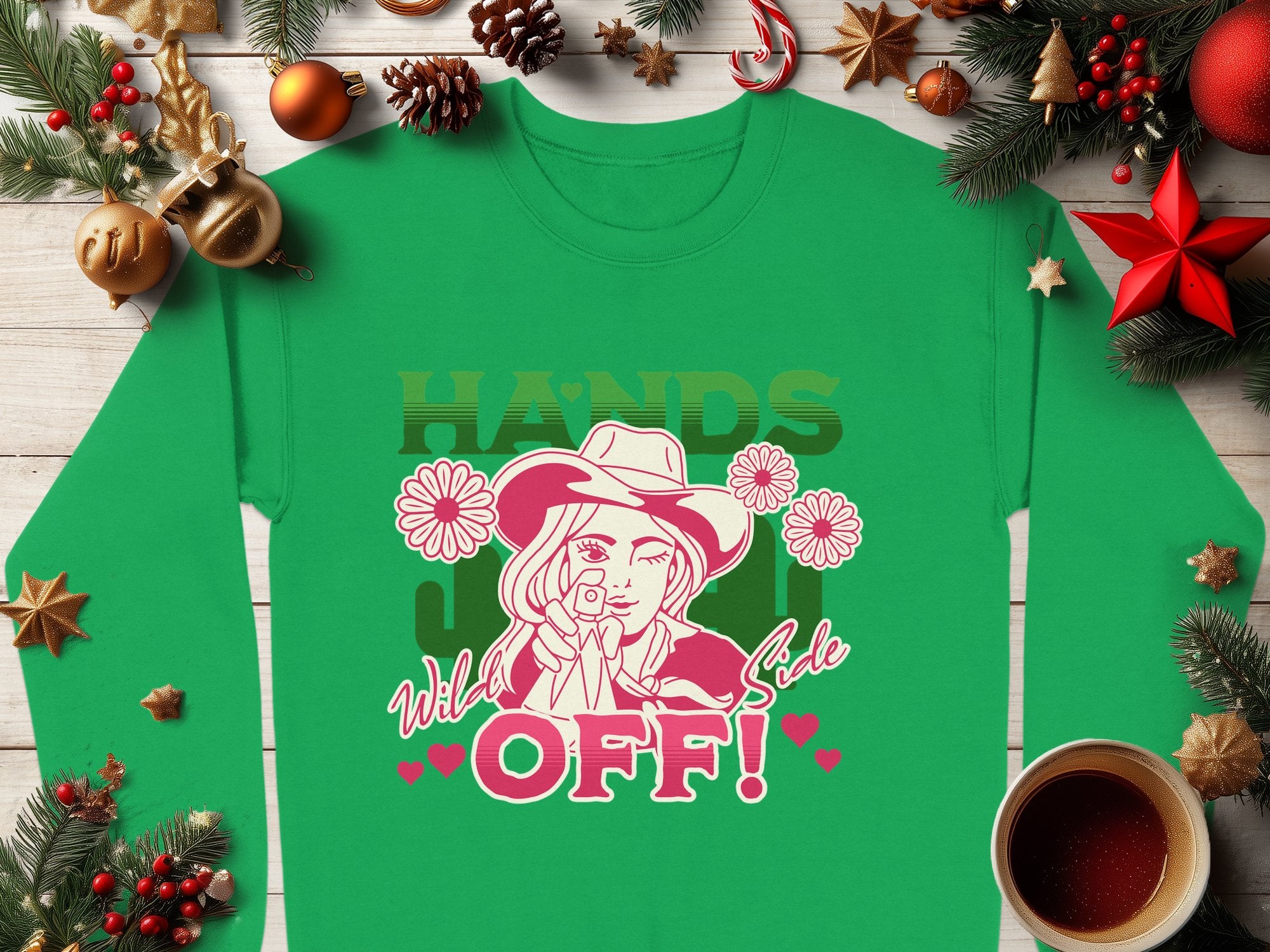 Discover Garment Graphics Wild Side Sweatshirt in green, boasting bold graphics of a person with a rose and the text HANDS OFF! It features holiday accents like pine branches, ornaments, candy canes, and coffee. Available in unisex sizing for ultimate comfort.