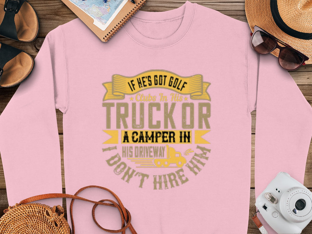A Garment Graphics pink sweatshirt features a humorous print: If hes got golf clubs in his truck or a camper in his driveway, I dont hire him, displayed on wood with accessories like a hat, sunglasses, notebook, and shoes—a great choice for unique design lovers.