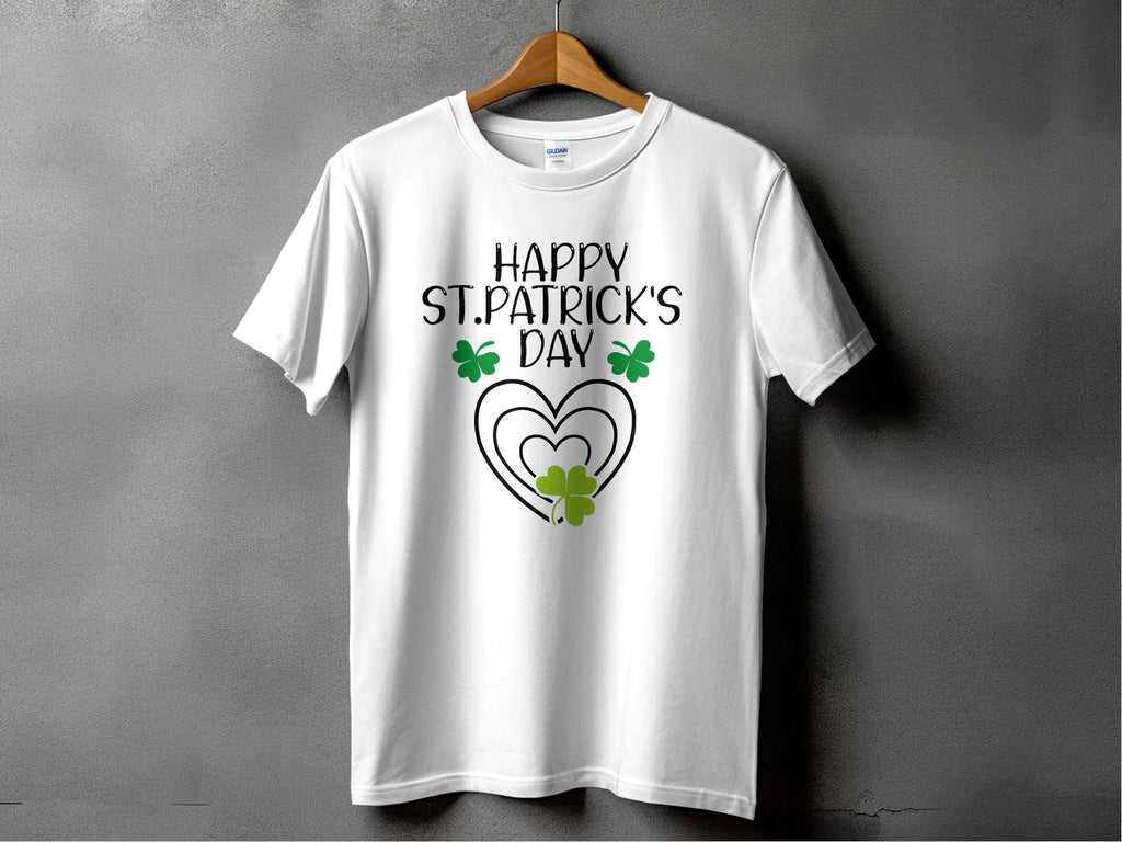 Garment Graphics offers a festive graphic T-shirt featuring a Happy St. Patricks Day design with a heart and shamrocks. It hangs stylishly on a wooden hanger against a gray backdrop, ready for celebration in style.