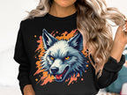 A person with long, wavy hair sports a Garment Graphics sweatshirt featuring a fierce wolf graphic. The design showcases a colorful wolf with orange eyes and an open mouth over a splattered background, highlighting their wild side indoors.