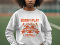 A person in a Garment Graphics white sweatshirt with an orange soccer ball graphic and the text Born to Play, One Goal - One Dream, Young Squad! highlights unisex sizing against a blurred outdoor backdrop.