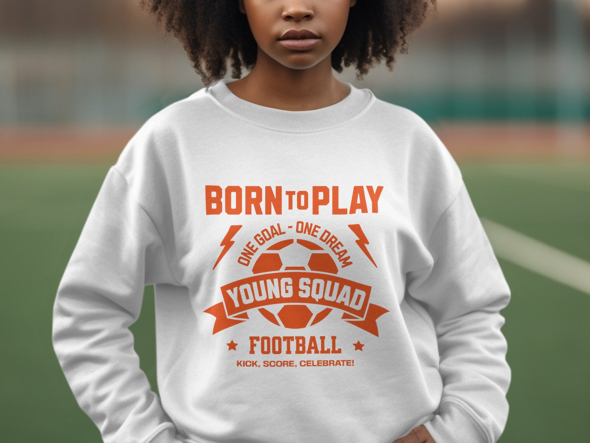 A person in a Garment Graphics white sweatshirt with an orange soccer ball graphic and the text Born to Play, One Goal - One Dream, Young Squad! highlights unisex sizing against a blurred outdoor backdrop.