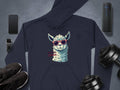 A navy llama hoodie with a classic fit from Garment Graphics features a cartoon llama in funny sunglasses and No Prob-Llama text. Its laid flat, surrounded by a smartphone, smartwatch, wireless speaker, black sneakers, and adjustable dumbbells.