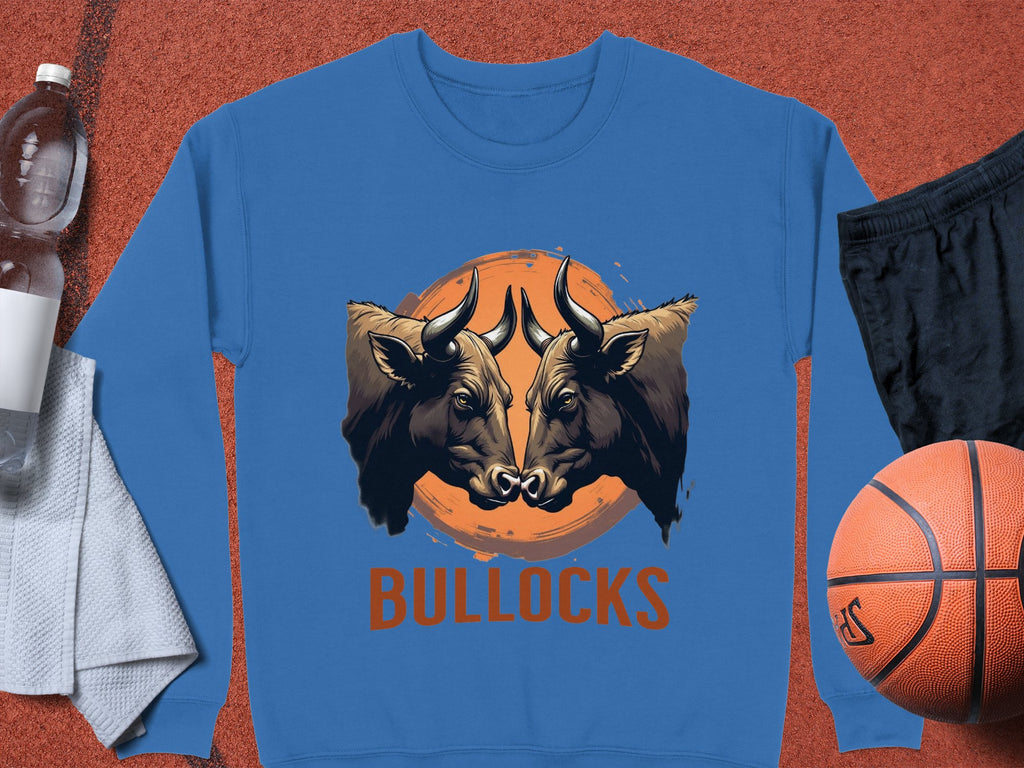 Garment Graphics blue sweatshirt showcases two bulls against an orange sun with BULLOCKS below. This unisex piece is styled with a water bottle, towel, black shorts, and a basketball.