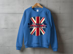 A blue unisex sweatshirt by Garment Graphics hangs on a wooden hanger against a concrete wall. It showcases a distressed Union Jack and the bold statement Dont Blame Me, I Didnt Vote For Him, making it a striking addition to any wardrobe.