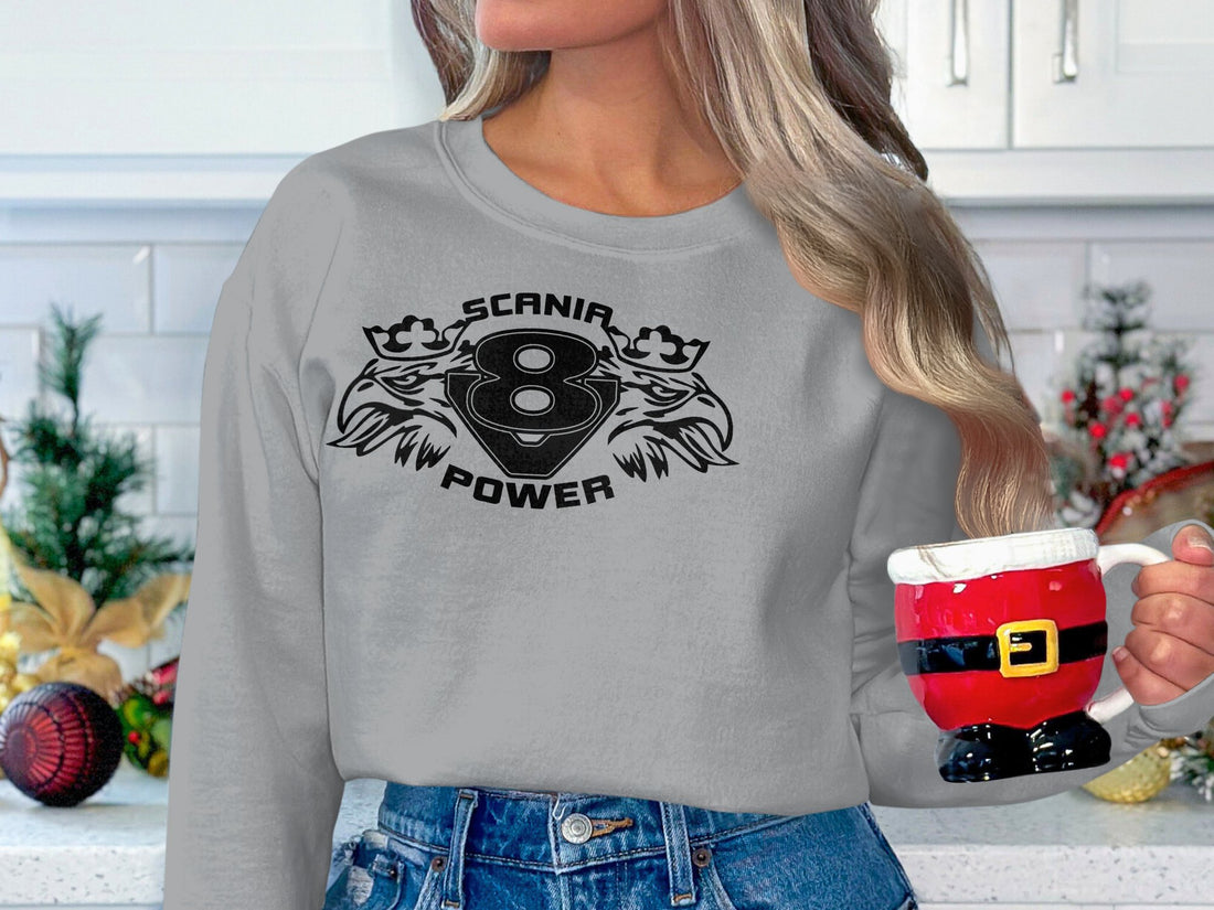 A person outdoors dons a stylish white sweatshirt from Garment Graphics with SCANIA POWER, two stylized animals, and the number eight printed on it. The blurred sports field background enhances the allure of this Scania Power V8 sweatshirt.