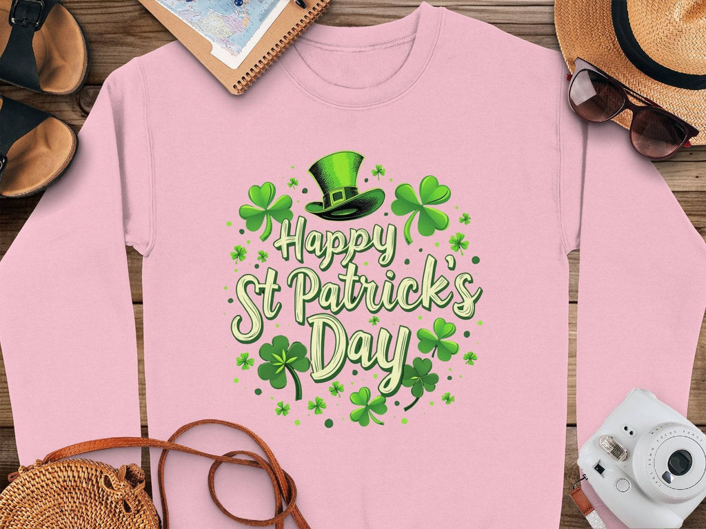 Garment Graphics pink shamrock graphic sweatshirt, with Happy St. Patricks Day among green shamrocks and a leprechaun hat, exudes festive cheer. Displayed on wood with a straw hat, sunglasses, notepad, sandals, and a camera nearby, its the perfect celebration ensemble.