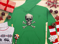 Trendsetting green hoodie by Garment Graphics with a skull and crossbones motif, laid on a wooden surface. Its accompanied by wrapped gifts, a reindeer pattern sweater, pinecones, candy cane, red berries, star decorations, and snowflakes.