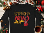 Garment Graphics trendy sweatshirt boasts Music Never Sleeps in vibrant yellow and red with a guitar graphic, ideal for music lovers. It’s adorned with festive décor like pine cones, ornaments, and a cozy coffee cup on a wooden surface.