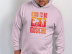 Wearing Garment Graphics white unisex hoodie, adorned with vibrant red and orange musician silhouettes and BORN TO BE A MUSICIAN text, makes a perfect choice for music lovers seeking a colorful statement piece.