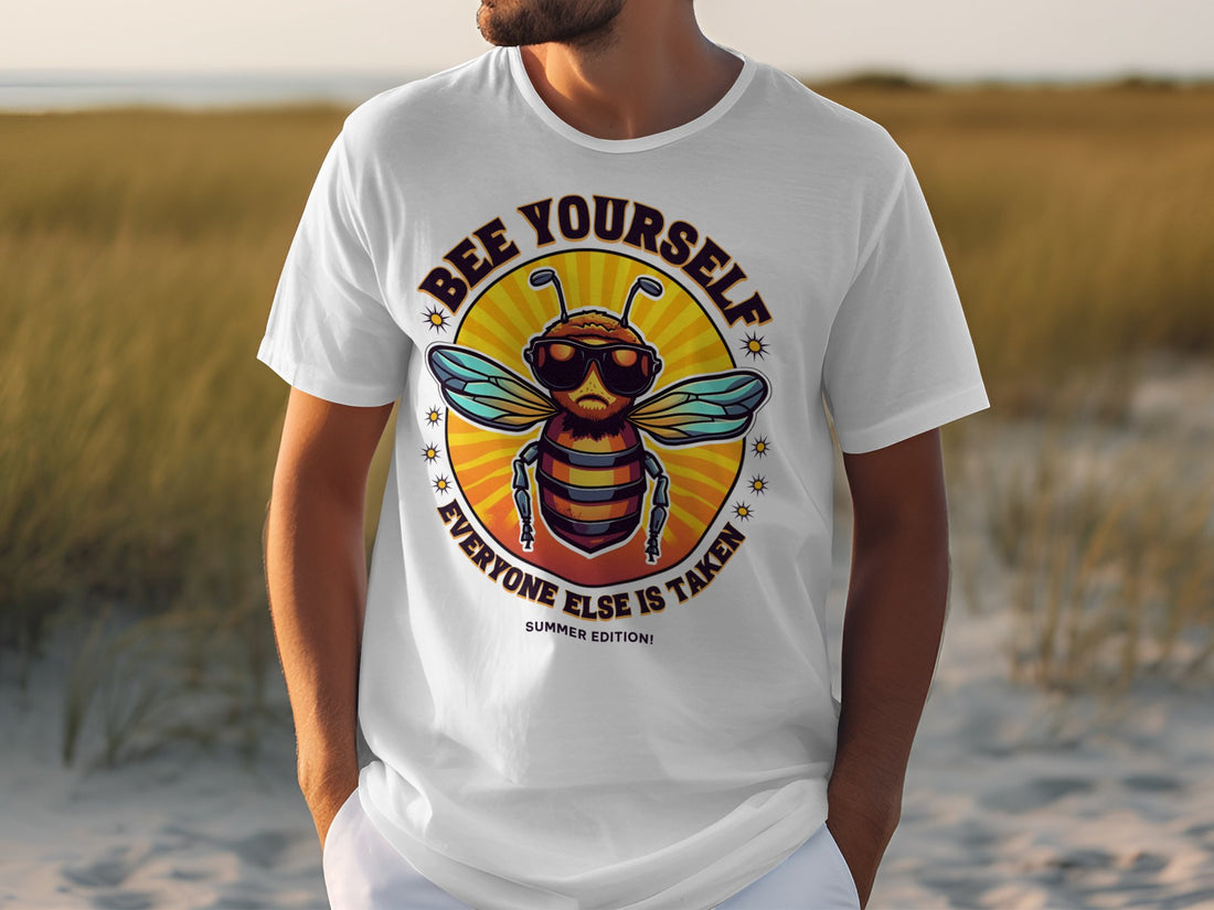 Wearing a Garment Graphics white tee with a bee in sunglasses, the words Bee Yourself, Everyone Else Is Taken surround the bee. This stylish design is set against a grassy landscape and clear sky and is part of the Every One Else Is Taken T-Shirts collection with family sizing.