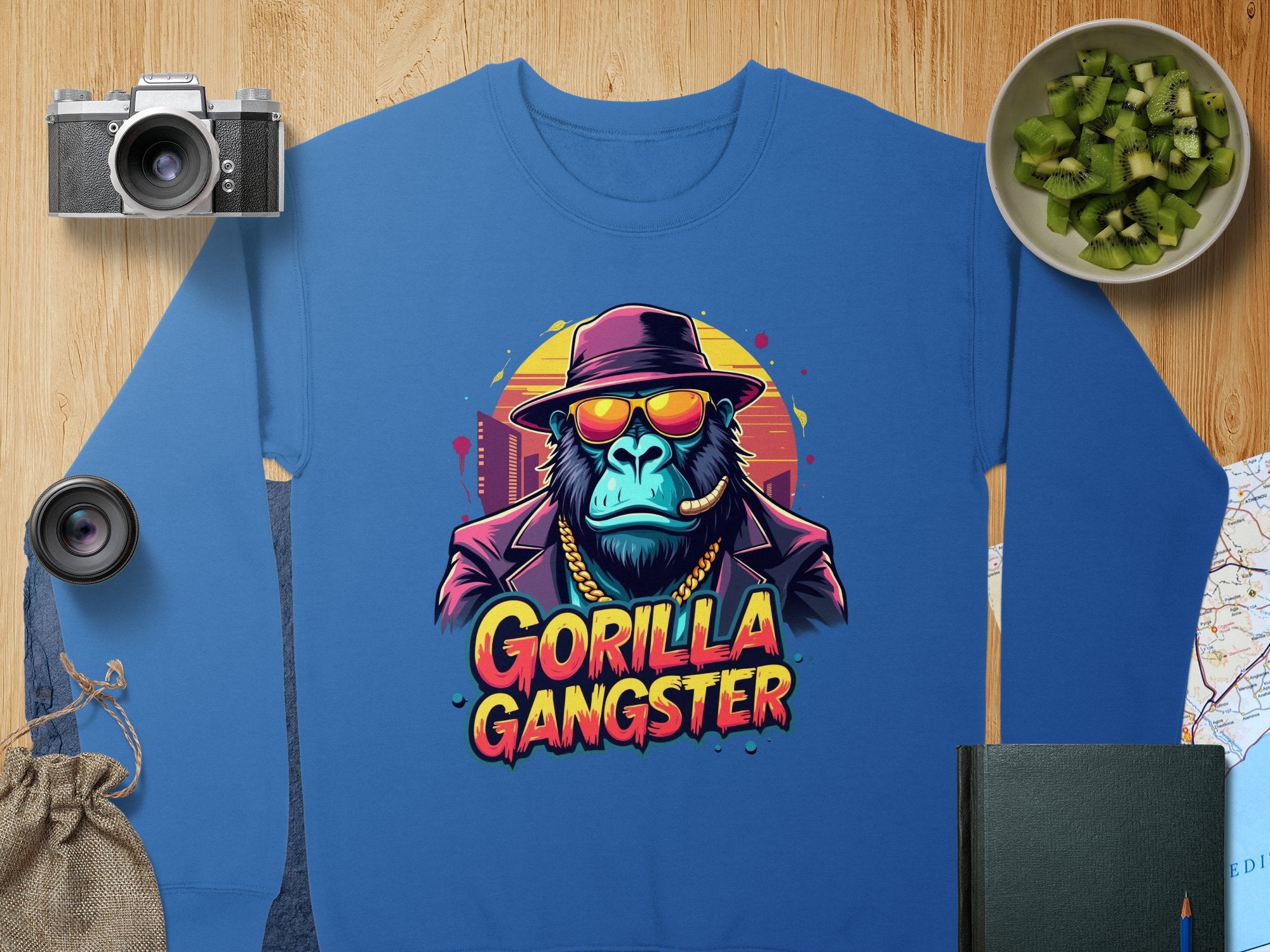 Garment Graphics presents an urban sweatshirt featuring a gorilla in a hat and sunglasses, smoking a cigar. Gorilla Gangster is printed among motifs like a camera, photo lens, cucumber bowl, map, and notebook—ideal for bold aesthetic enthusiasts.