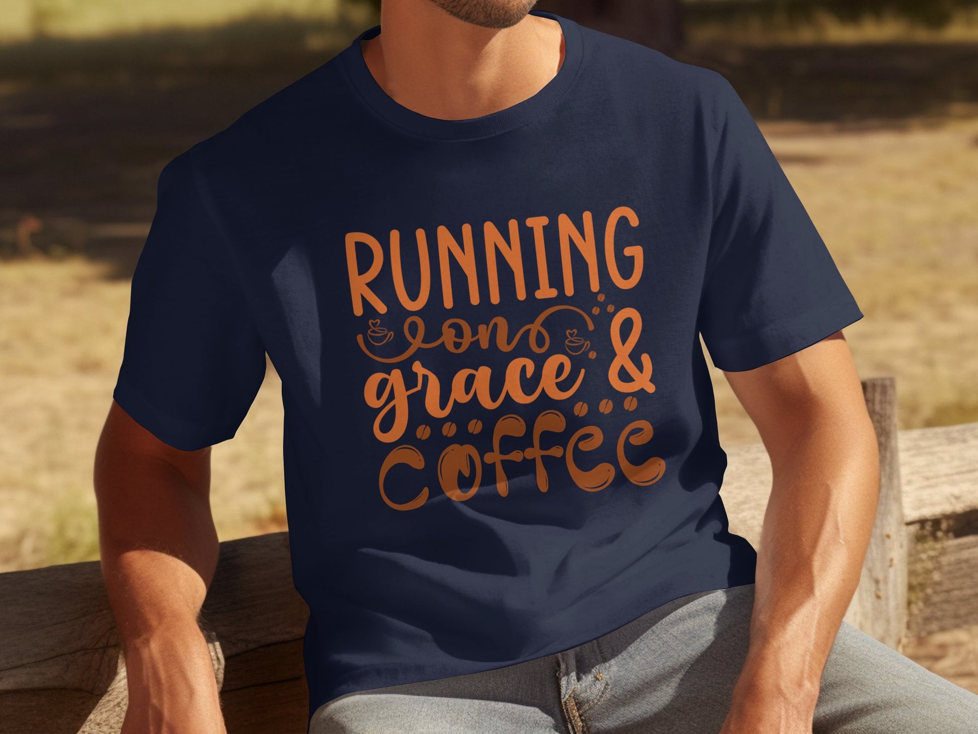 A person enjoys the sunlight on a wooden bench, dressed in a dark blue Garment Graphics T-shirt featuring the uplifting phrase Running on Grace & Coffee with small coffee cup icons.