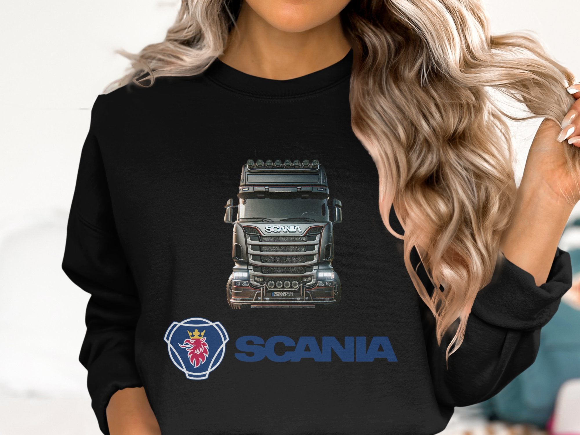 Sporting long, wavy blonde hair, a person wears a Garment Graphics crewneck sweatshirt featuring Scania trucks and logo. Perfect for truck enthusiasts, the design is prominent as the individual is partially visible from shoulders up.