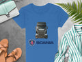 Garment Graphics blue Scania T-shirt, featuring a truck image and logo, is displayed on a gray surface. Ideal for automotive enthusiasts, its accompanied by sandals, a turquoise bag, striped shirt, wristwatch, and fern leaf.