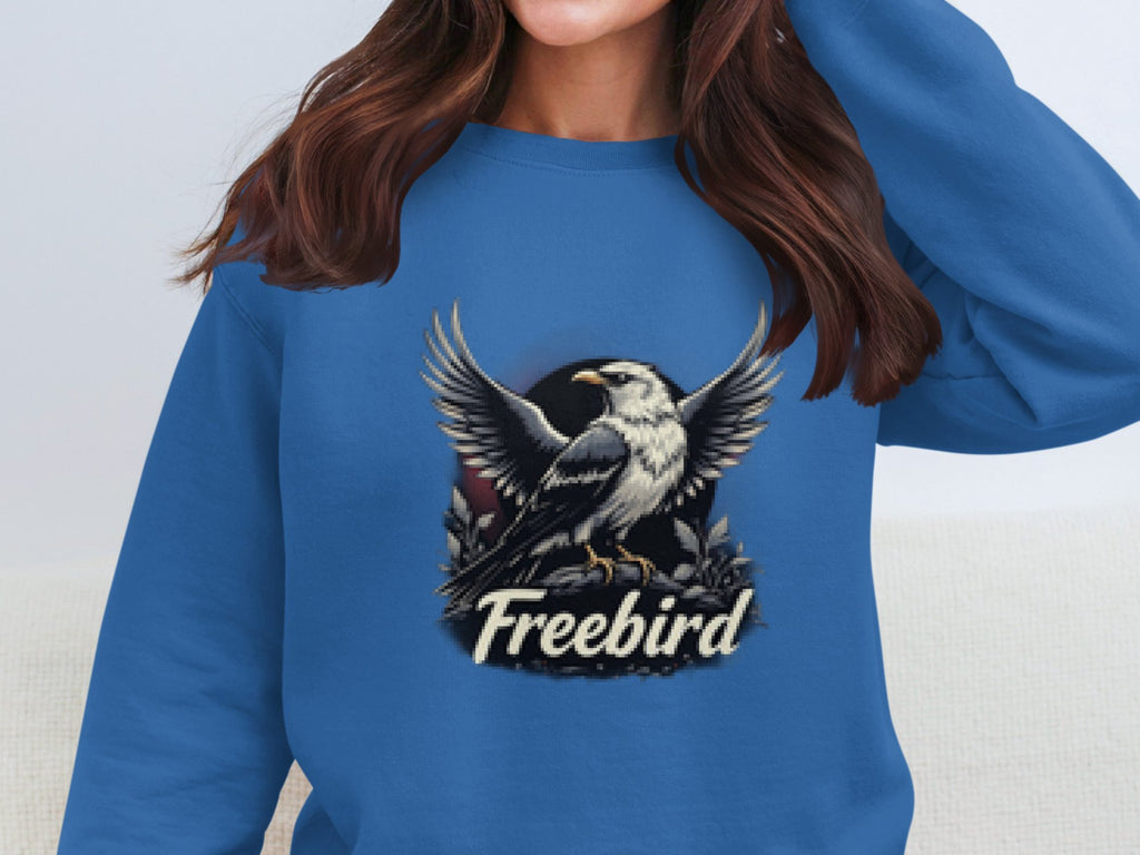 The individual sports a blue Garment Graphics Freebird Graphic Sweatshirt boasting an eagle with outstretched wings, and the text Freebird beneath. Their long brown hair cascades down as they are partially cropped from the image.