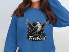 The individual sports a blue Garment Graphics Freebird Graphic Sweatshirt boasting an eagle with outstretched wings, and the text Freebird beneath. Their long brown hair cascades down as they are partially cropped from the image.