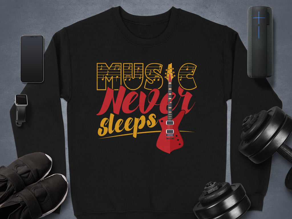 A vibrant black sweatshirt featuring a red guitar and Music Never Sleeps in vintage yellow and red text by Garment Graphics, perfect for music lovers. It’s styled with a smartphone, smartwatch, portable speaker, black sneakers, and adjustable dumbbells on a gray surface.