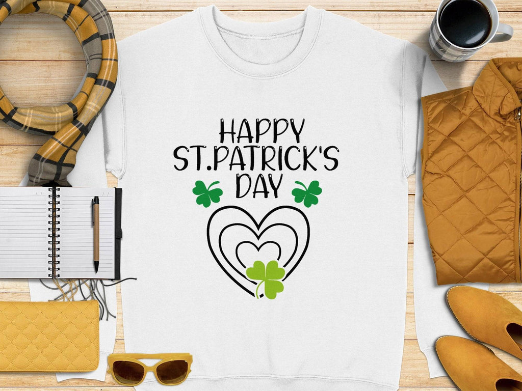 The Garment Graphics festive sweatshirt with Happy St. Patricks Day and green clovers pairs well with a plaid scarf. Also featured are a black pen, notebook, yellow purse, sunglasses, quilted jacket, and striped coffee mug on wood complementing the clover design ensemble.