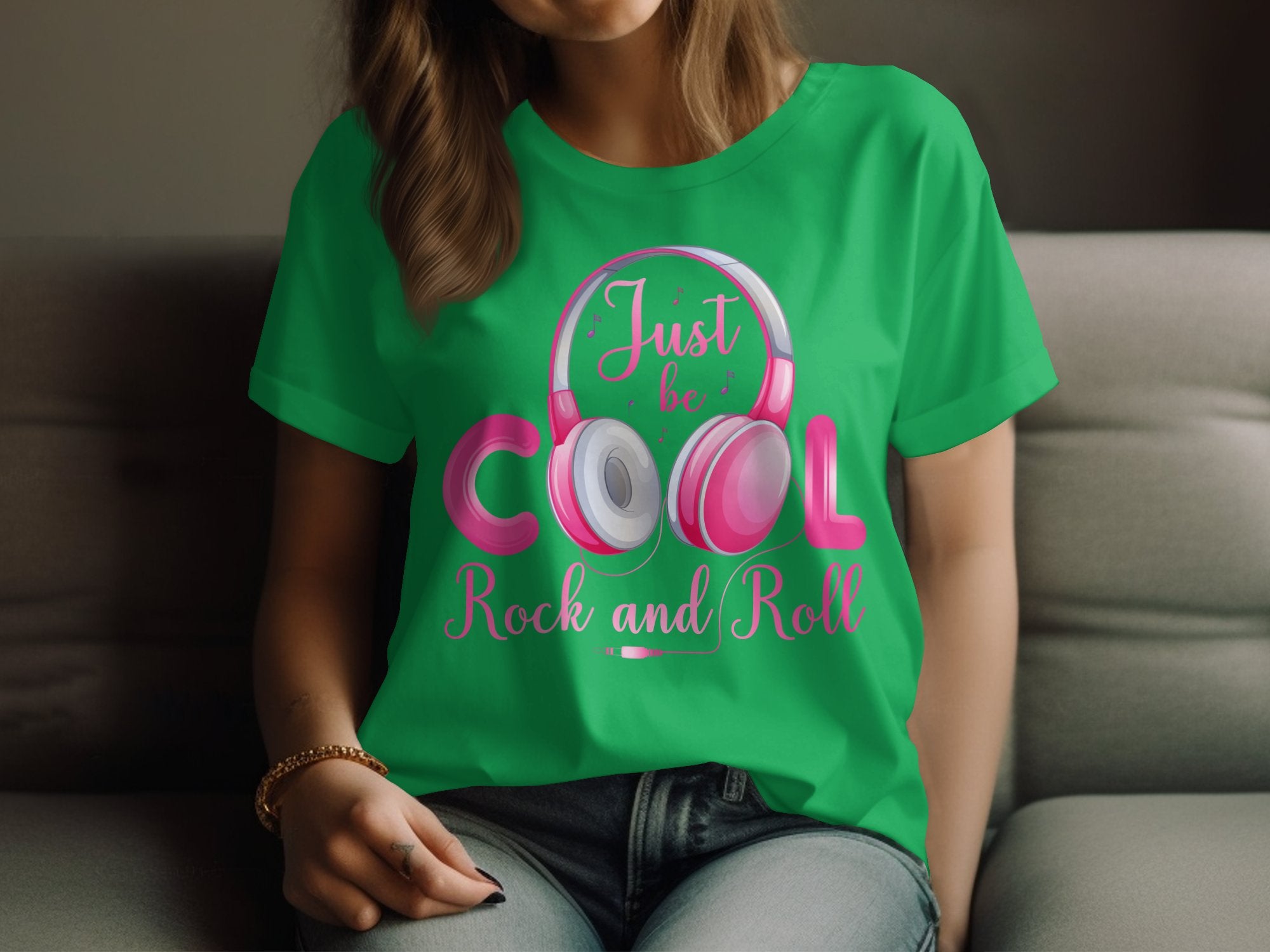 A music lover wears a green Garment Graphics t-shirt featuring Just be COOL Rock and Roll and headphone graphics. Seated against a softly blurred background, the essence of headphones t-shirts for rock and roll fans is perfectly showcased.