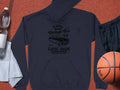 A dark blue hoodie from Garment Graphics, featuring a classic fit and London city vintage car illustration, is displayed next to a basketball, gray towel, plastic water bottle, and dark shorts—ideal for automobile lovers.