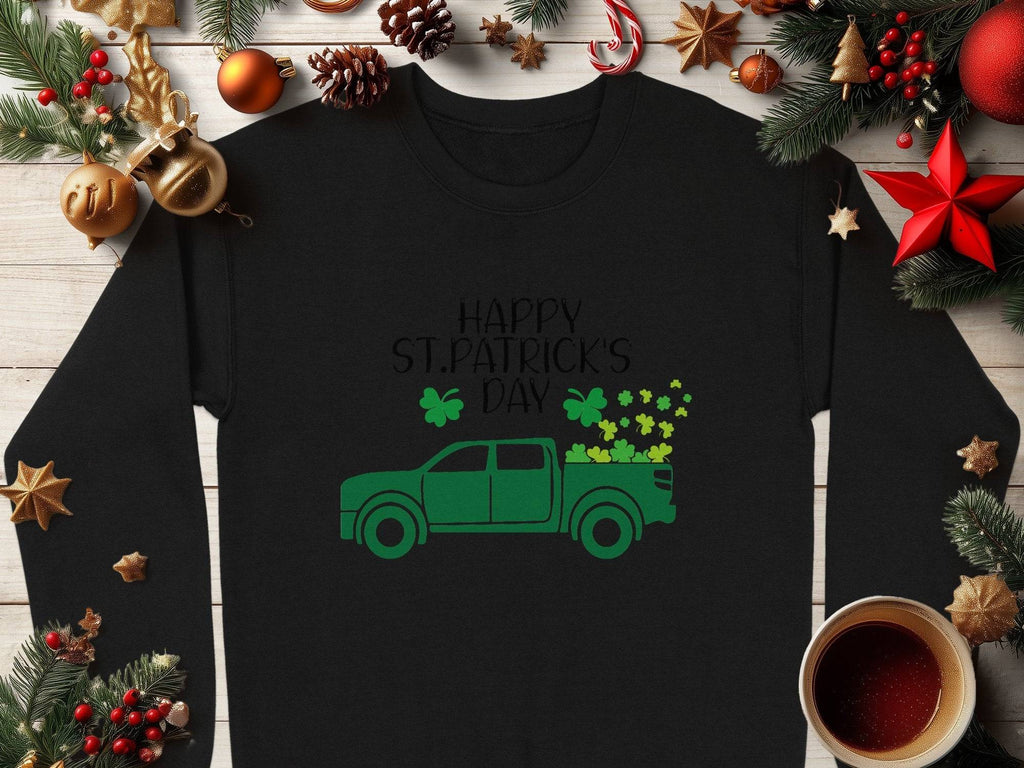 A Garment Graphics sweatshirt features Happy St. Patricks Day in green above a shamrock-laden truck, surrounded by festive pine cones, stars, a red bow, and a coffee cup in the corner.
