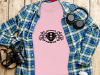 A pink Garment Graphics t-shirt with Scania V8 Power and an eagle head design sits on a wooden surface, paired with a blue plaid shirt, black headphones, camera, and a white coffee cup lid.