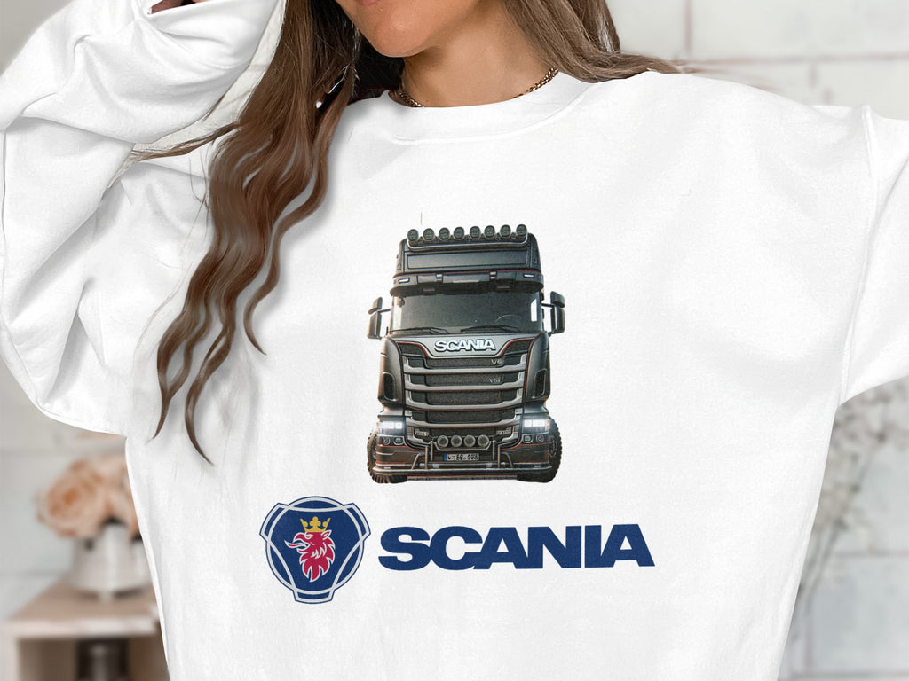 Wearing a Garment Graphics white graphic crewneck sweatshirt, the individual sports a bold Scania truck image on the front, complemented by the blue Scania logo and brand name below. The persons face is not visible. Ideal for truck enthusiasts.