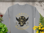 Garment Graphics presents a gray biker-style sweatshirt featuring a skull with goggles, a winged helmet, and the text Liberty Motorcycles Specialist Blackpool 2023 adorned with wrenches and stars. Surrounded by green plants and yellow flowers, it captures Liberty Motorcycles bold spirit.