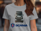 A person with long brown hair wears a gray Garment Graphics T-shirt featuring a detailed illustration of a Scania truck on the front. Ideal for automotive enthusiasts, this graphic tee prominently displays the Scania logo and name in blue below the truck.