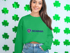 Wearing a green Garment Graphics Scania logo sweatshirt with unisex sizing, the person smiles against a shamrock backdrop. With long brown hair and denim shorts, theyre perfectly dressed for casual outings.