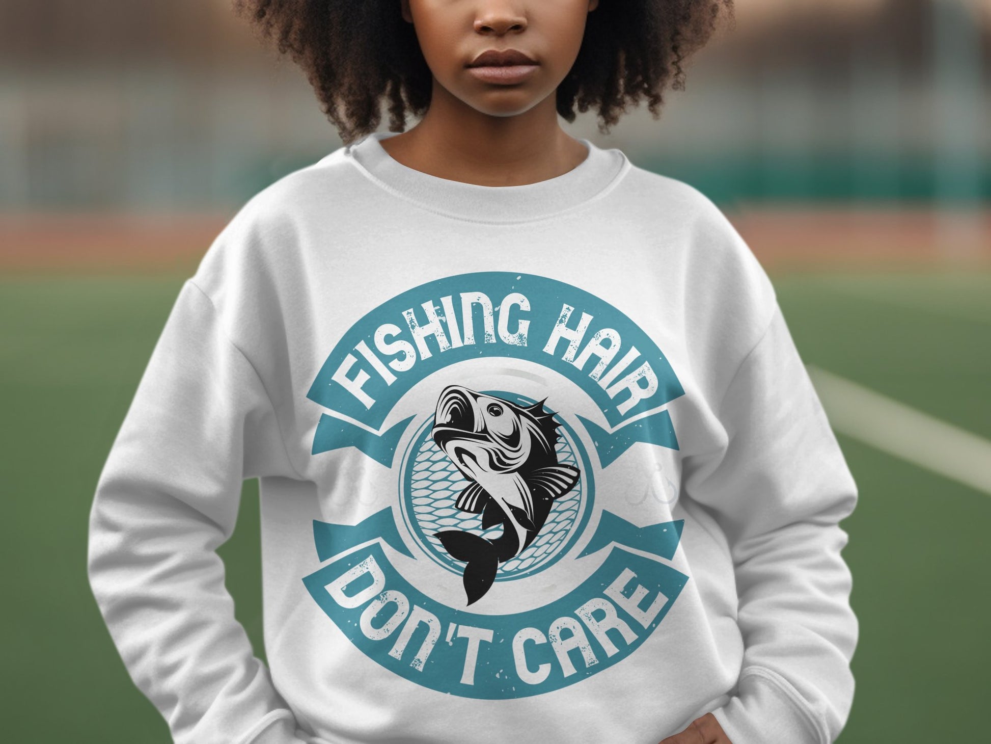 A fishing enthusiast wears a Garment Graphics white sweatshirt featuring a fish graphic and the playful blue text Fishing Hair Dont Care. The artistically blurred background shows hints of greenery and a fence.