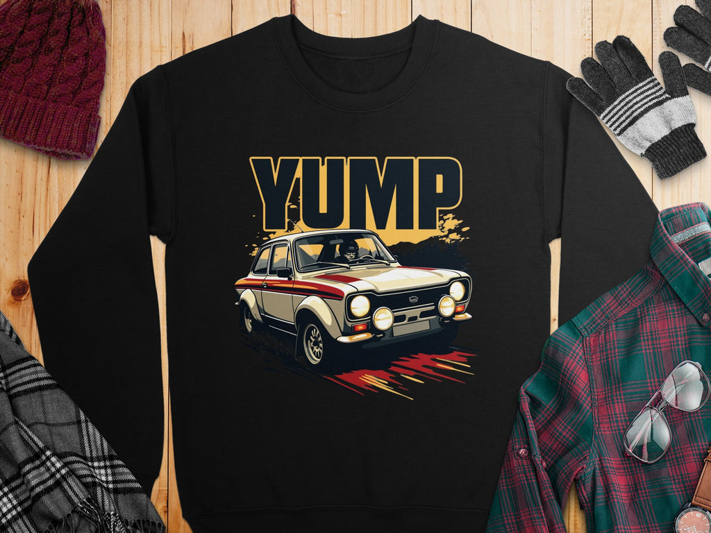 Garment Graphics black sweatshirt with a rally car graphic, racing stripes, and YUMP text. Displayed with a plaid shirt, scarf, gloves, beanie on a wooden background.