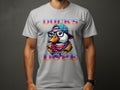 A person flaunts a Garment Graphics T-shirt featuring a stylized duck wearing glasses, a cap, and a colorful scarf. Bold letters encircle the duck with DUCKS DOPE, creating an eye-catching design that captures attention effortlessly.