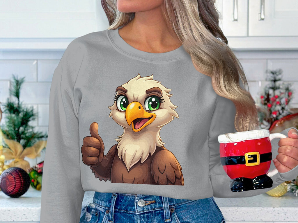 Dressed in a Garment Graphics unisex cartoon eagle sweatshirt, someone gives a thumbs up while holding a red Santa suit-shaped mug. The kitchen teems with festive decorations in the background.