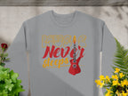 The Garment Graphics sweatshirt showcases Music Never Sleeps in bold red and yellow, with a vivid red guitar graphic. Ideal for music lovers, it’s beautifully set against green plants and yellow flowers on a light gray backdrop.
