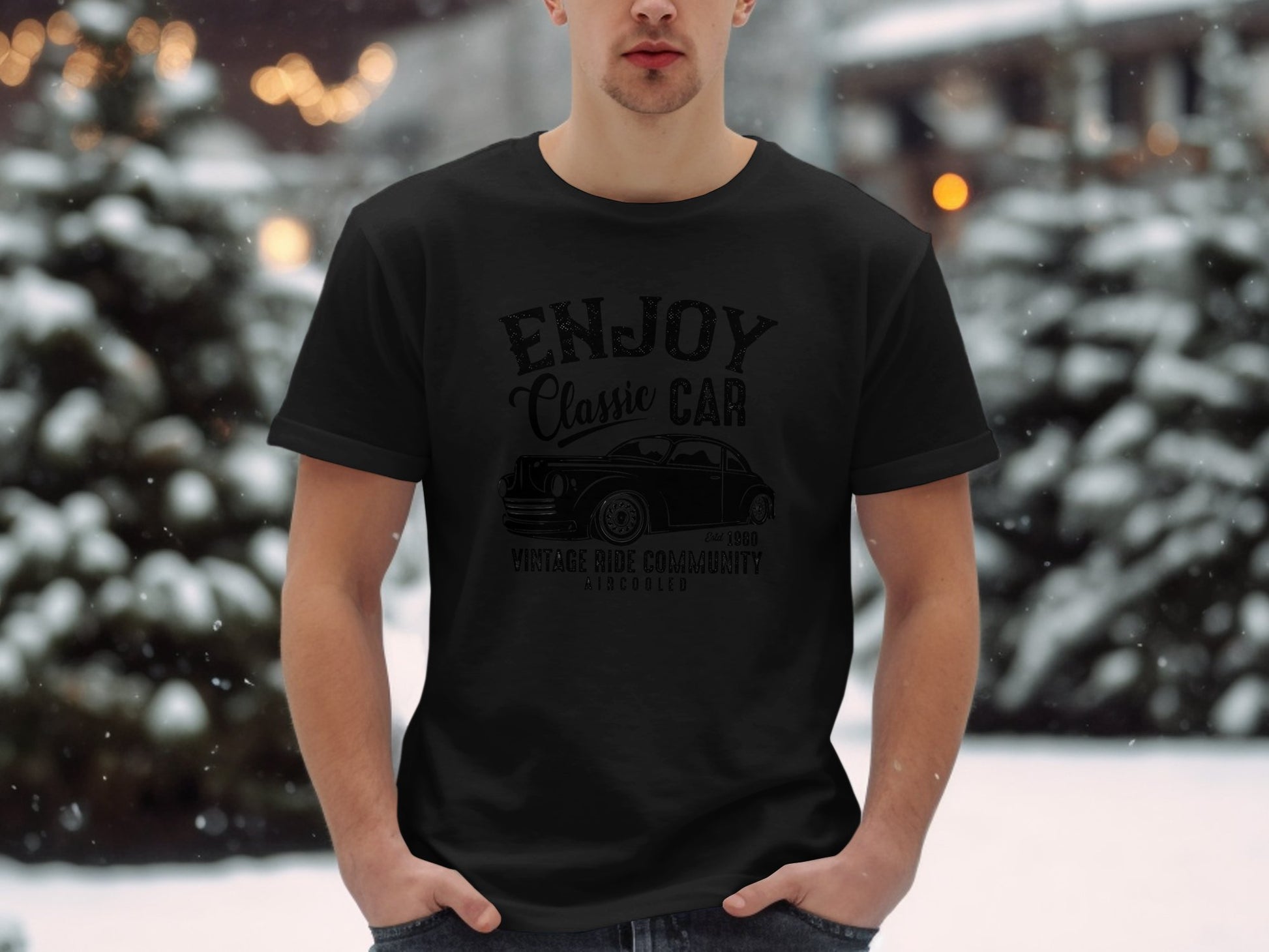 In a snowy setting, a person wears a Garment Graphics black T-shirt adorned with Enjoy Classic Car and a vintage vehicle illustration. Ideal for car lovers, snow-covered trees set the scene.