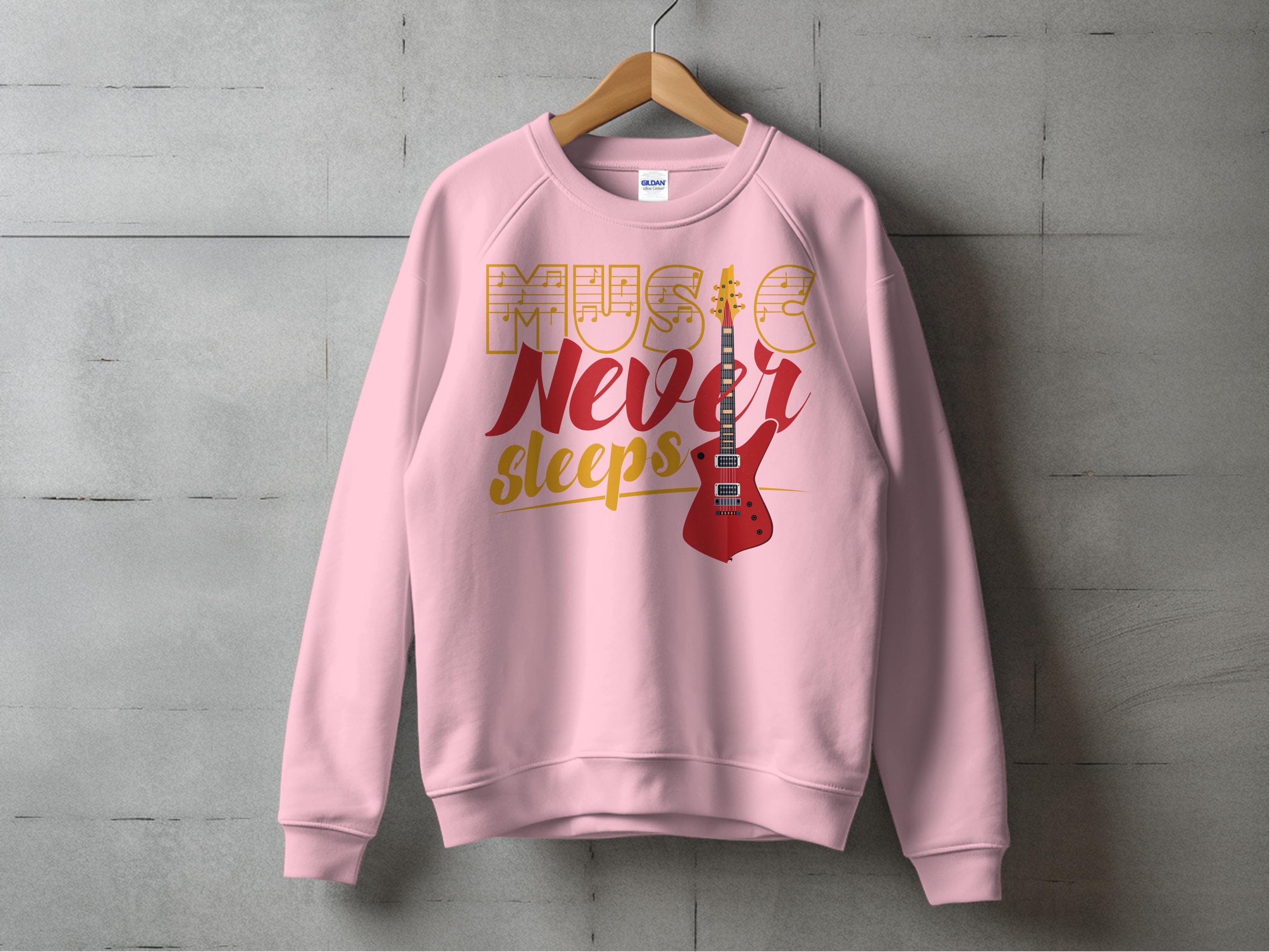 A vibrant pink Garment Graphics sweatshirt hangs on a wooden hanger against a concrete wall, ideal for music fans. It features Music Never Sleeps in bold and showcases a striking red electric guitar graphic on the right side.