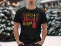 A person stands in a snowy setting wearing a black Garment Graphics t-shirt, crafted from 100% cotton, featuring the text Music Never Sleeps and a bold red guitar design.